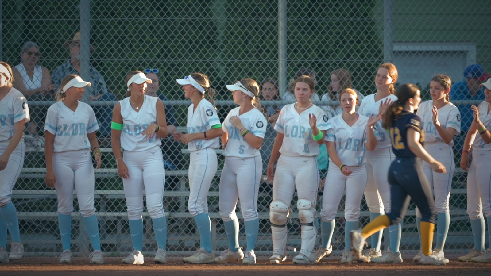 A softball team in white uniforms in the dugout
